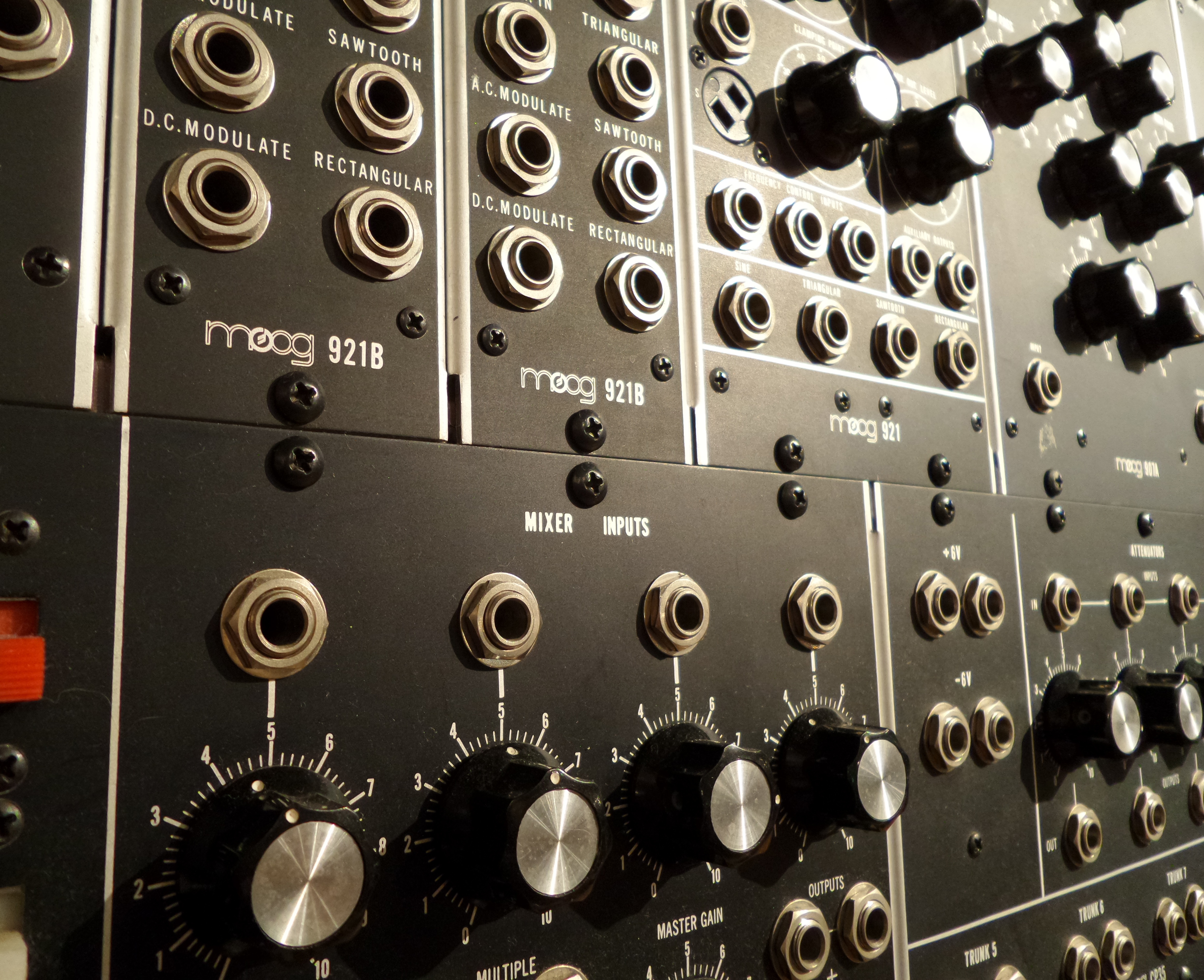 Close view of a Moog modular synthesizer showing knobs, switches, sockets, and patch cords.